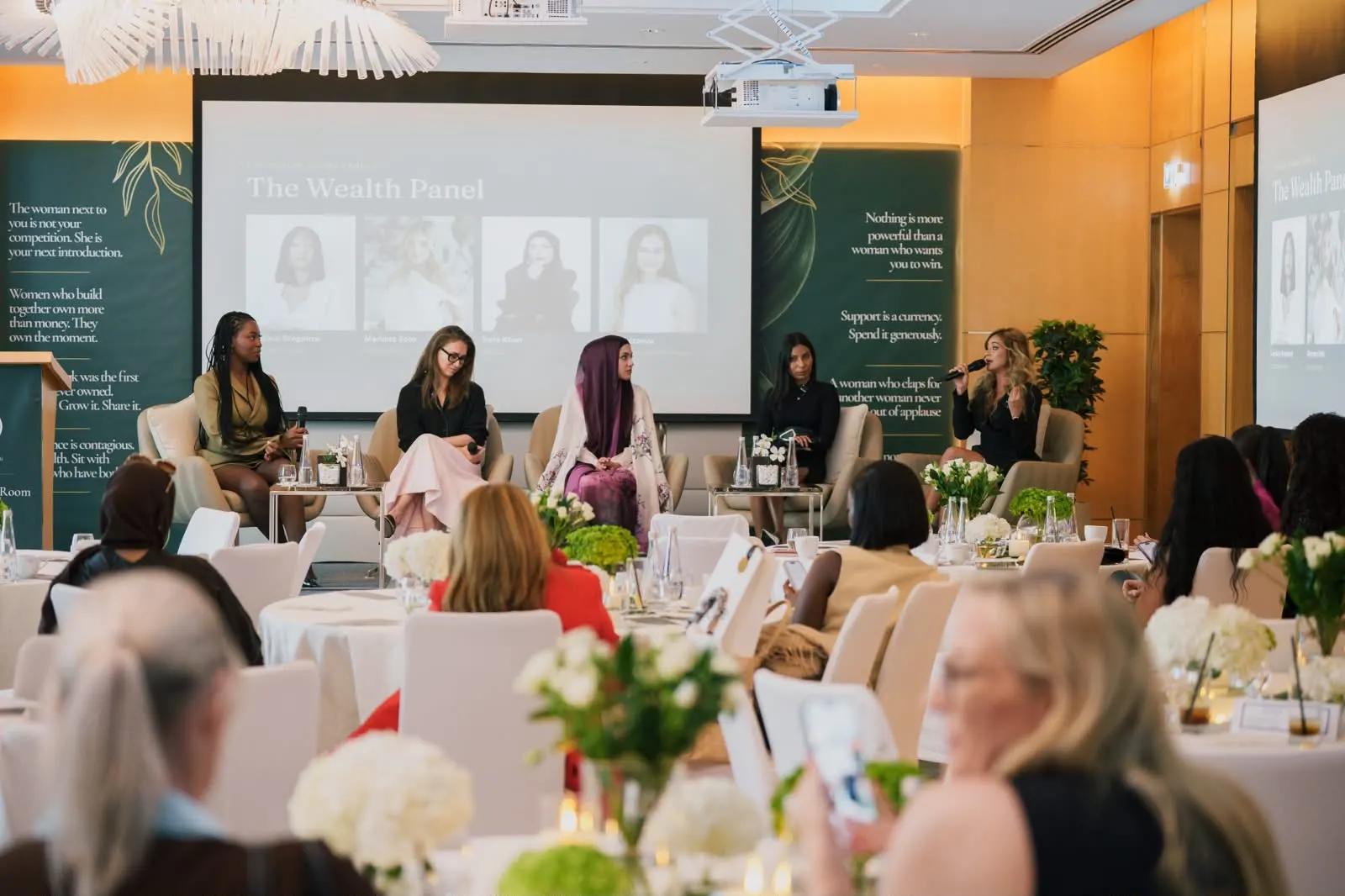 The Wealth Room panel on stage, seen from behind a room of women seated at round tables.