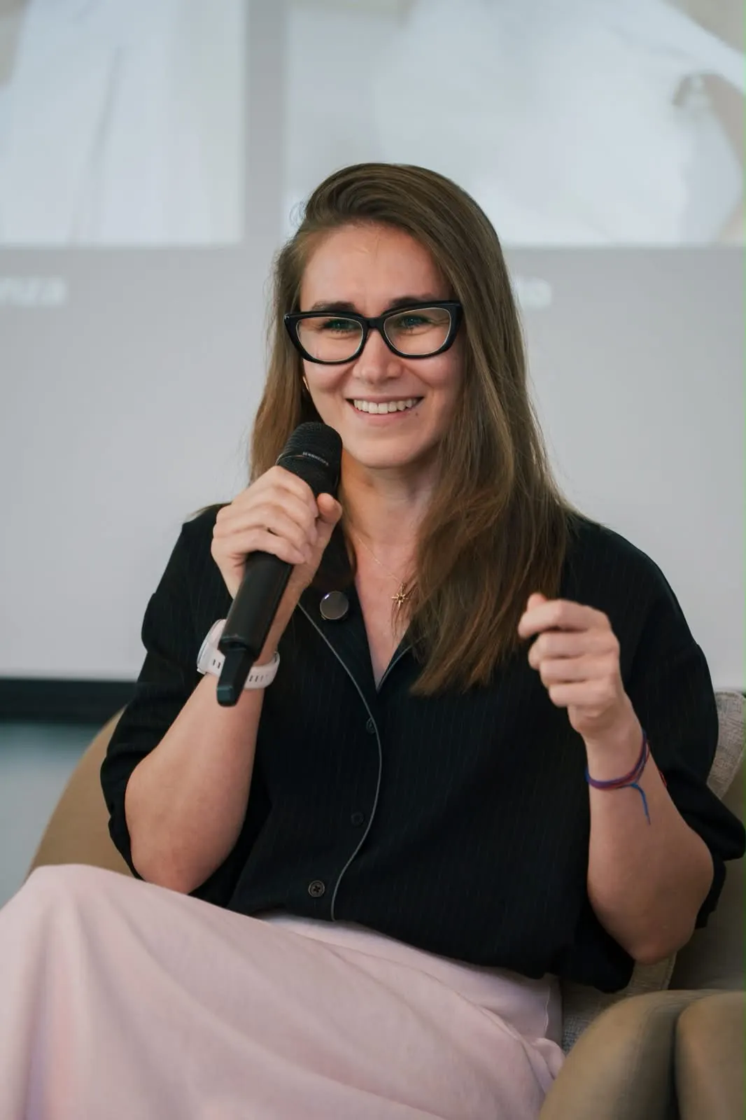 A speaker in glasses speaking into a microphone.